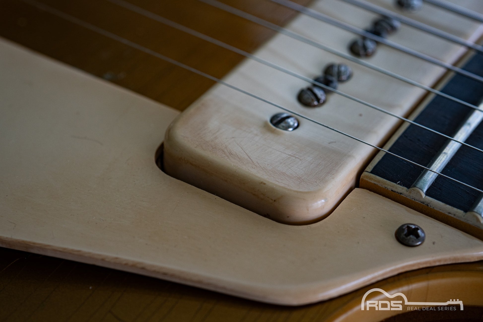 Close-up of a guitar's neck and fretboard with a blurred background