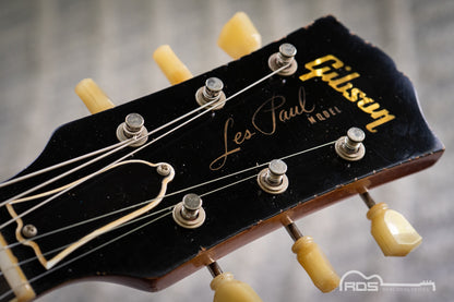 Gibson Les Paul guitar headstock with visible branding on a blurred background