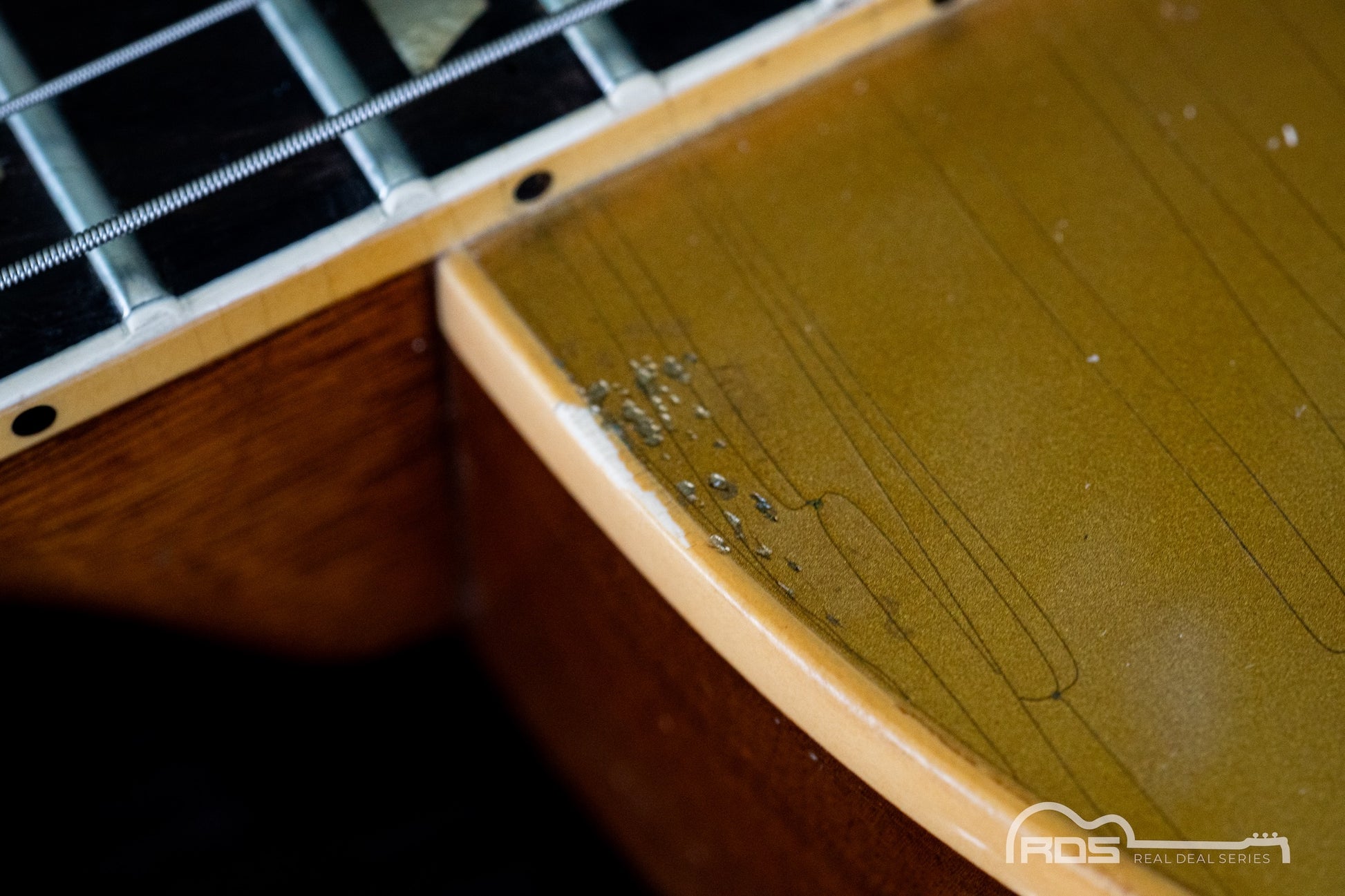 Close-up of a guitar's fretboard and headstock with visible wear.