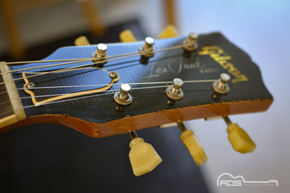Gibson Les Paul guitar headstock with tuning pegs on a blurred background