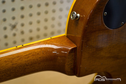 Close-up of a wooden guitar neck with a pegboard background