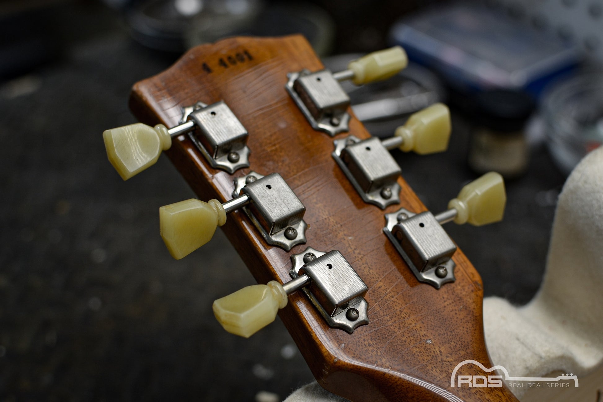 Close-up of a guitar headstock with tuning pegs on a blurred background