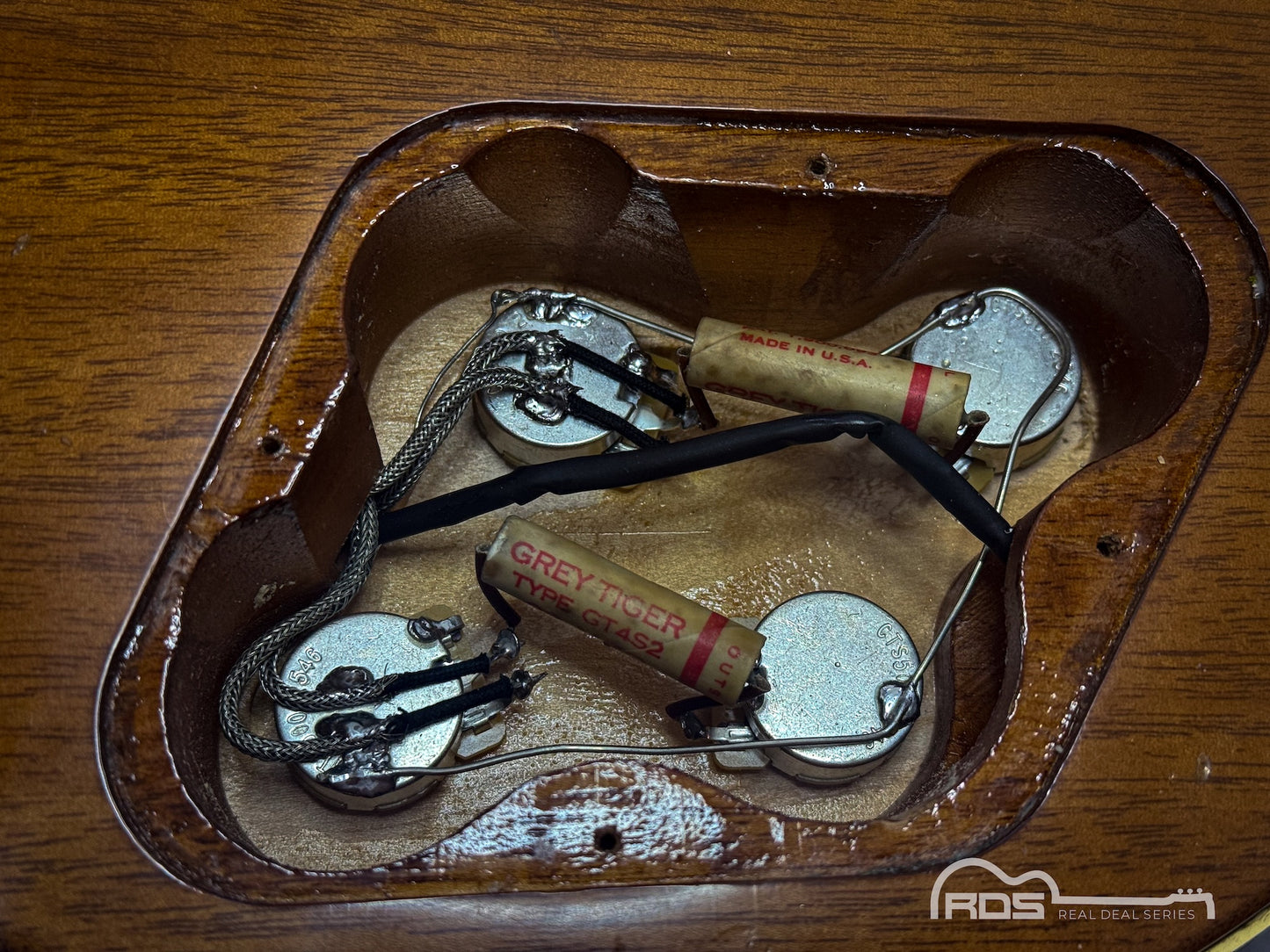 Guitar with visible wiring on a wooden surface